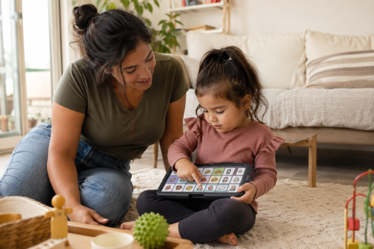 Young child using an AAC device with a caregiver during everyday home play